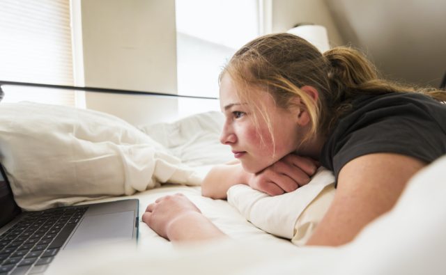 teen age girl looking at laptop in bed